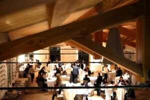 Cena di gala vista dall'alto tra le capriate dell'Ex Lanificio Carotti, con tavoli rotondi e ospiti