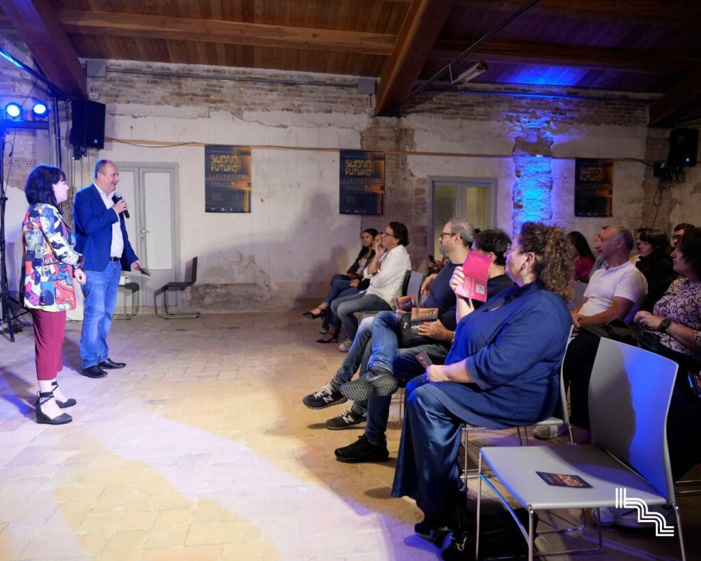 Presentazione di Suono Futuro all'Ex Lanificio Carotti durante la prima edizione Liberazioni (2025): pubblico seduto nella sala con capriate in legno e locandine del festival sulla parete