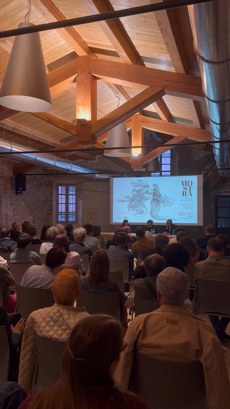 La sala gremita durante la presentazione, con la grafica della mostra proiettata.
